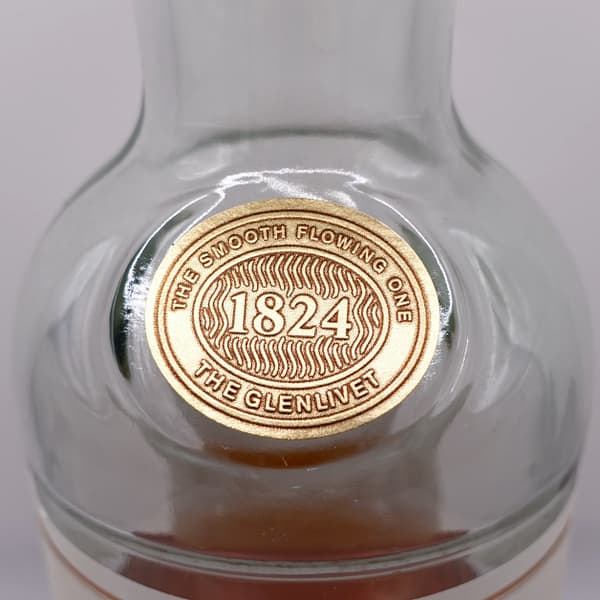 Detail of the Glenlivet 12 bottle showing the 1824 company foundation date and the motto "The smooth flowing one"