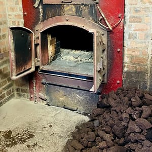 Picture of the malting kiln furnace at Springbank Distillery with a stack of peat ready to be used for drying the malted barley