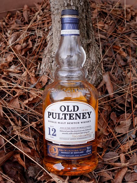 Image of the Old Pulteney 12 bottle on a backdrop of dried leaves