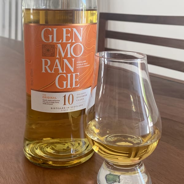 Glenmorangie 10 and gleinecairn glass containing whisky on a dark wooden table