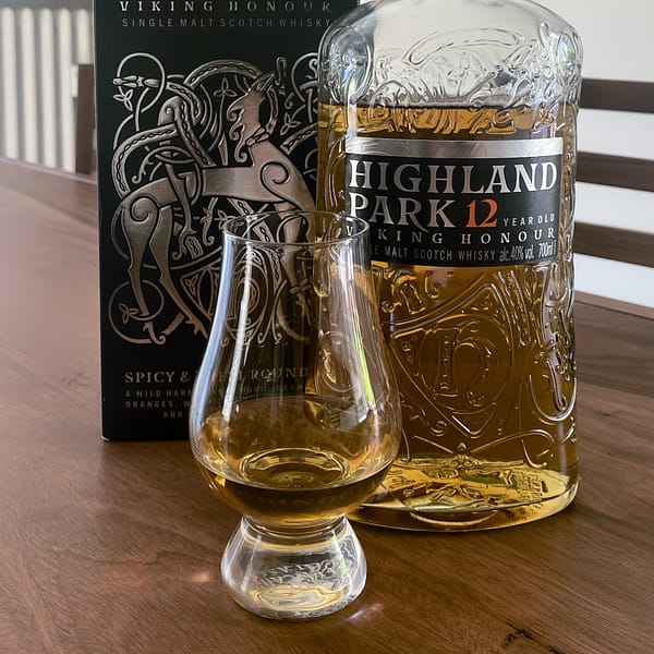 Picture showing the Highland Park 12 Viking Honour bottle and box with some of the same wehisky poured into a Glencairn glass