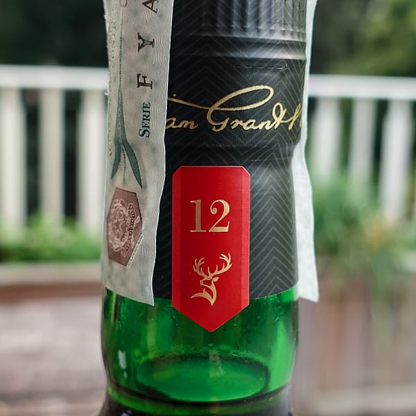 Glenfiddich 12 cap seal detail showing a red tab with the "12" age statement and the stag head logo