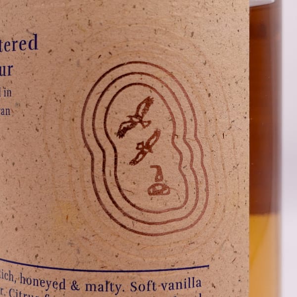 Detail of the Arran 10 year old bottle label showing two golden eagles and a pot still encased in an outline of the Isle of Arran