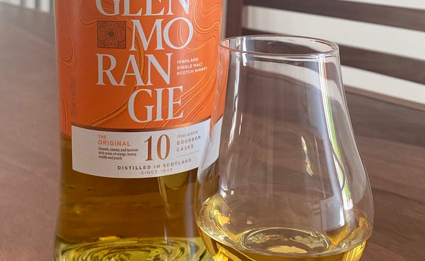 Glenmorangie 10 and gleinecairn glass containing whisky on a dark wooden table