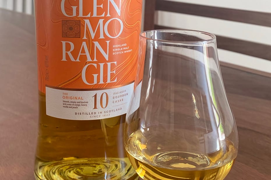 Glenmorangie 10 and gleinecairn glass containing whisky on a dark wooden table