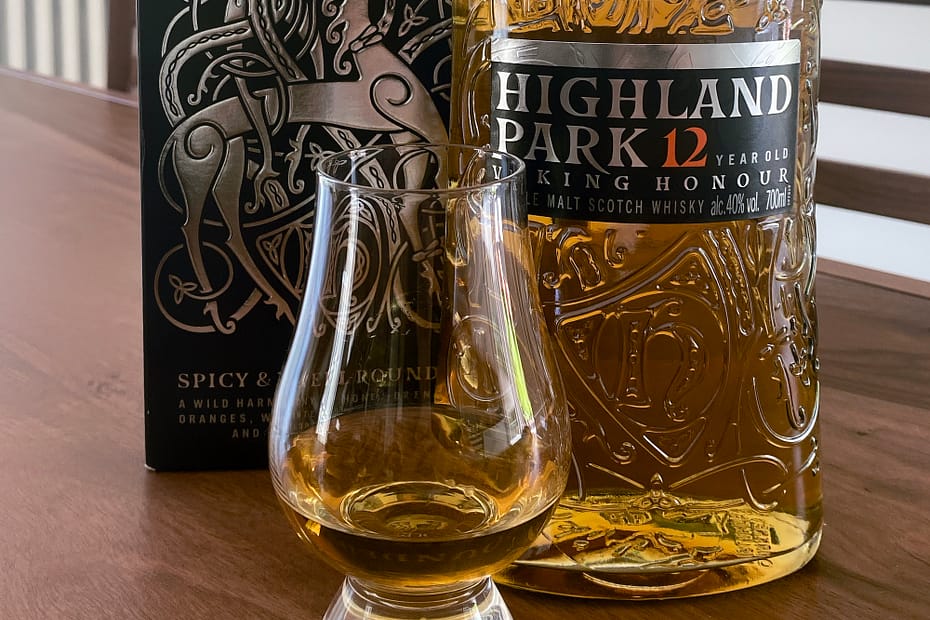 Picture showing the Highland Park 12 Viking Honour bottle and box with some of the same wehisky poured into a Glencairn glass